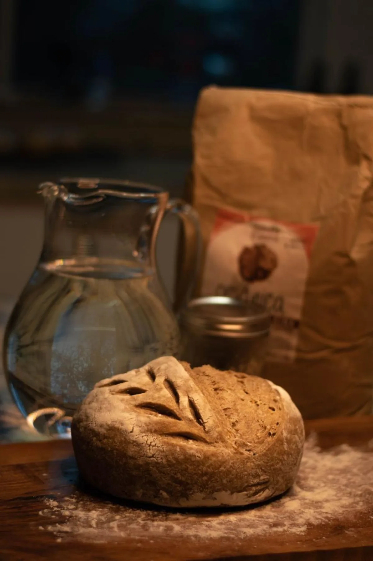 Hogaza de masa madre junto a una jarra de agua y harina